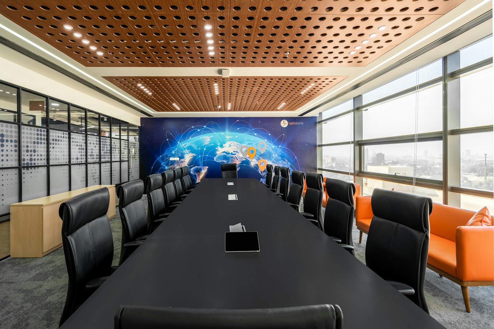 a conference room with a large black table and orange chairs